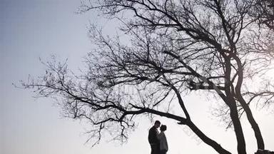 一对浪漫的约会情侣在大自然的一棵大树旁。